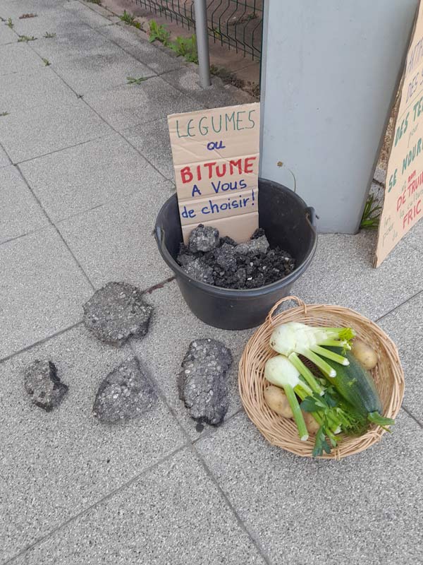 Seau de bitume et panier de légumes côte à côte avec l'inscription "Des légumes ou du bitume, à vous de choisir"