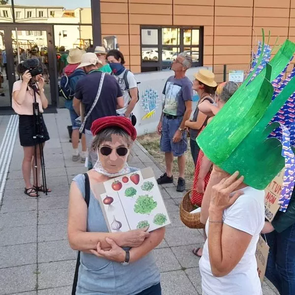 Militants coiffés de chapeau de paille, devant la CCRG, dont une déguisée en poireau