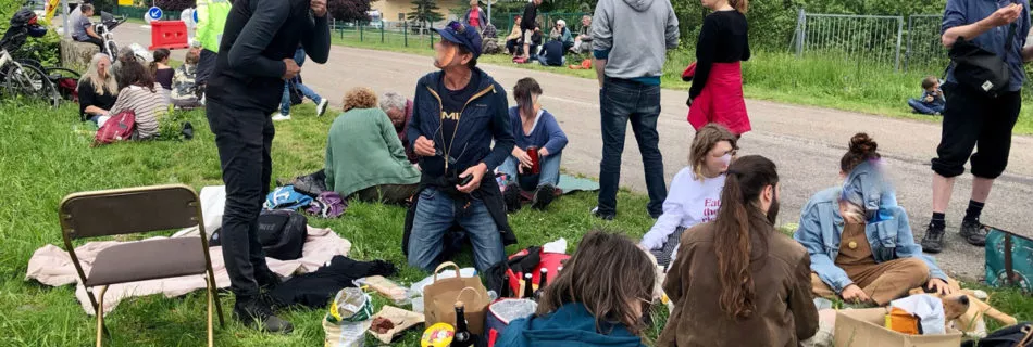 Groupe de personnes discutant et mangeant sur l'herbe non loin du terrain du Daweid à Issenheim.